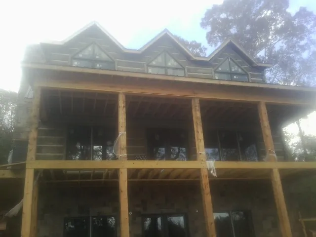 Dormers and porch framing on a large log home under construction — Roof Coating work by our crew in Reva