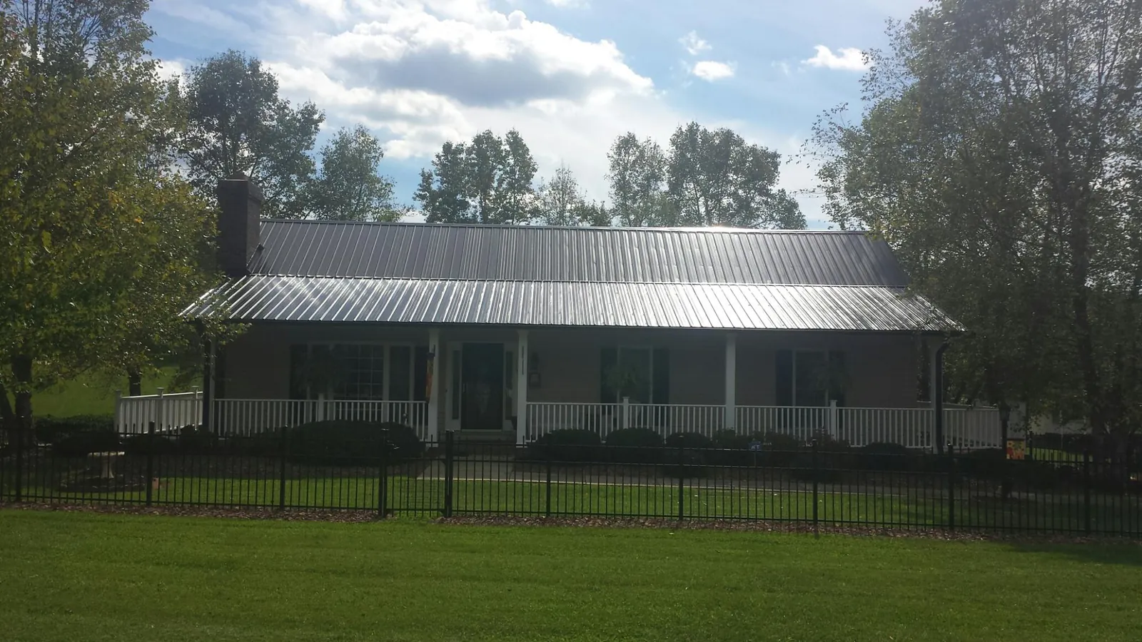 Gray metal roof on a brick ranch with a full width front porch — Gutter Guard Installation work by our crew in Reva