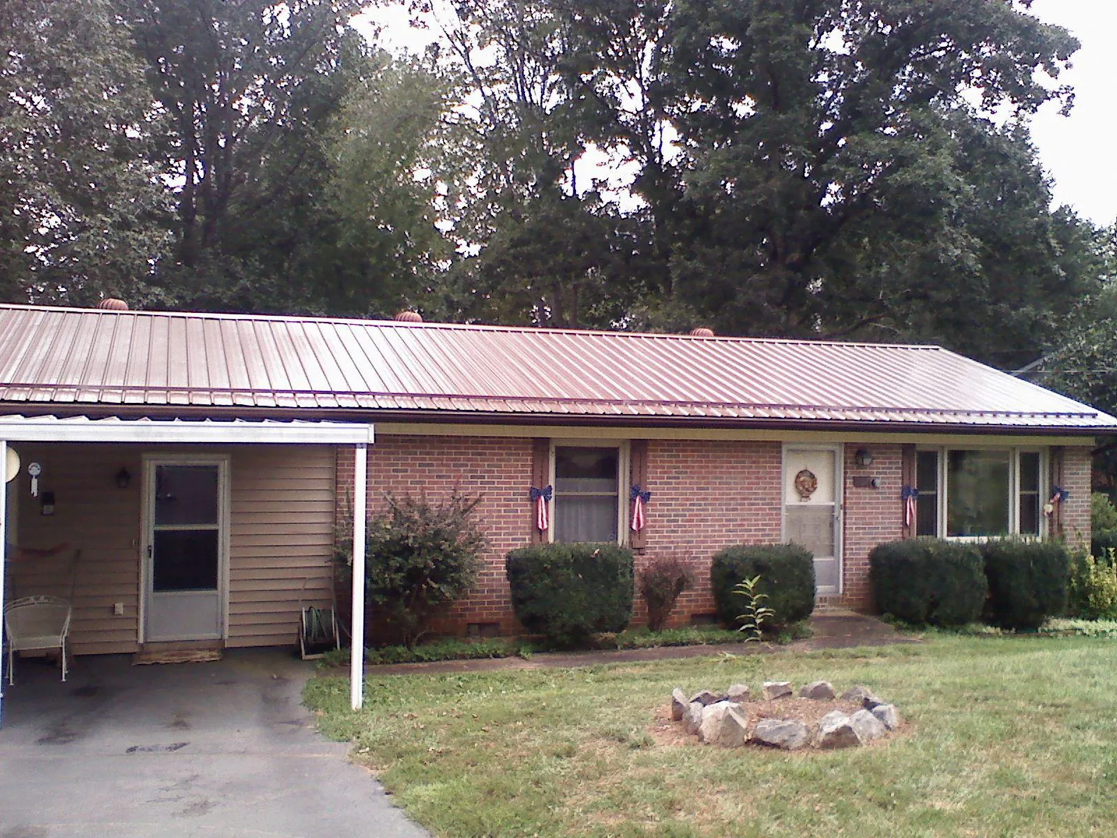 Bronze metal roof and carport on a brick ranch home — Roof Repair work by our crew in Reva