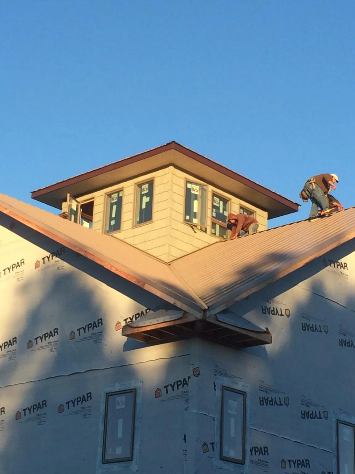 Roofers working around a rooftop cupola on a new metal roof at sunset — Roof Waterproofing in Reva by Roofing Brothers